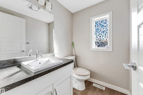 The bathroom features a modern vanity with a white rectangular sink and dark countertop, complemented by a large mirror and overhead lighting - 1624 33A Street, Edmonton, AB - Indoor Photo Showing Bathroom