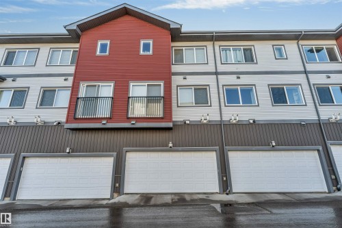 The property features a contemporary exterior with both red and light gray siding, multiple windows, and individual garage doors - 1624 33A Street, Edmonton, AB - Outdoor