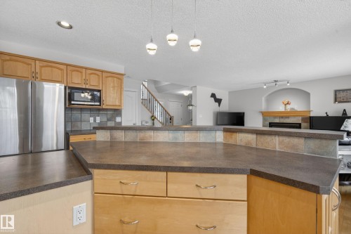 The kitchen features light wood cabinetry, stainless steel appliances, and a tiled backsplash - 1119 Rutherford Close, Edmonton, AB - Indoor Photo Showing Kitchen