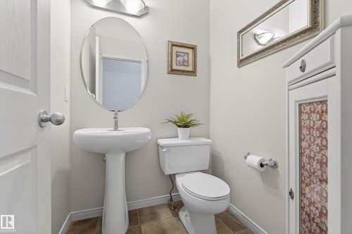 This bathroom features a pedestal sink, an oval mirror, and a toilet - 1119 Rutherford Close, Edmonton, AB - Indoor Photo Showing Bathroom