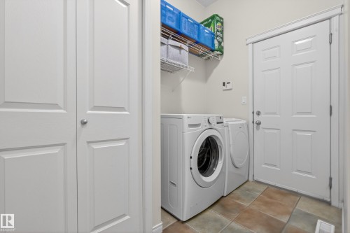 Dedicated laundry area featuring a washer and dryer, tiled flooring, and overhead shelving for storage - 1119 Rutherford Close, Edmonton, AB - Indoor Photo Showing Laundry Room