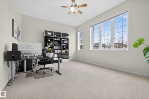 This spacious room features neutral-toned walls, light-colored carpeting, a ceiling fan, and large windows that provide ample natural light - 1119 Rutherford Close, Edmonton, AB - Indoor Photo Showing Office