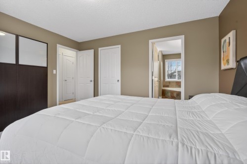 This bedroom features light brown walls and white trim, with a built-in dark wood structure containing two translucent panels - 1119 Rutherford Close, Edmonton, AB - Indoor Photo Showing Bedroom
