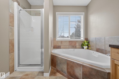 The bathroom features a corner soaking tub and a stand-up shower with a glass door - 1119 Rutherford Close, Edmonton, AB - Indoor Photo Showing Bathroom