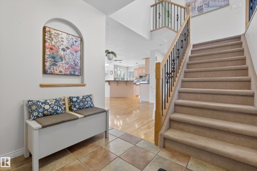 The entryway features tiled flooring, a carpeted staircase with a wooden handrail and black metal balusters, and an arched wall niche - 1119 Rutherford Close, Edmonton, AB - Indoor Photo Showing Other Room