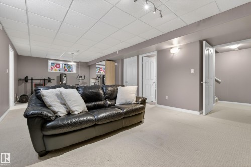 Finished living area featuring light-colored carpet, neutral-toned walls, and a drop ceiling with track lighting - 1119 Rutherford Close, Edmonton, AB - Indoor Photo Showing Other Room