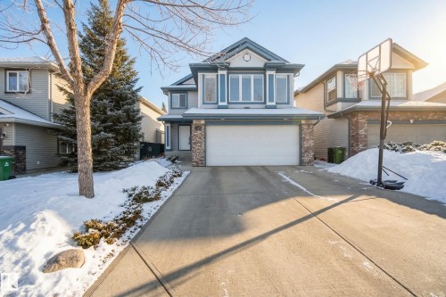 The property features a two-story exterior with light blue siding and stone accents, a double garage, and a concrete driveway - 1119 Rutherford Close, Edmonton, AB - Outdoor With Facade