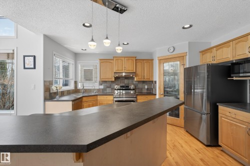 This kitchen features light wood cabinetry, dark countertops, and stainless steel appliances - 1119 Rutherford Close, Edmonton, AB - Indoor Photo Showing Kitchen With Double Sink