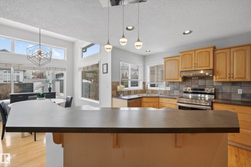 The kitchen features light wood cabinetry, stainless steel appliances, and a tiled backsplash - 1119 Rutherford Close, Edmonton, AB - Indoor Photo Showing Kitchen