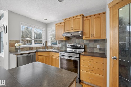 The kitchen features light wood cabinetry, stainless steel appliances, and a tiled backsplash - 1119 Rutherford Close, Edmonton, AB - Indoor Photo Showing Kitchen With Double Sink
