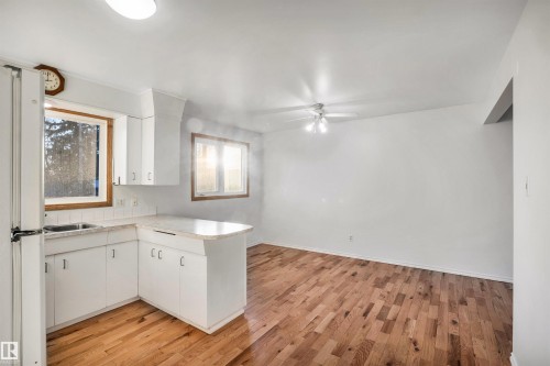 Kitchen with a peninsula, light countertops, white cabinets, freestanding refrigerator, and light wood-style floors - 11231 41 Avenue, Edmonton, AB - Indoor
