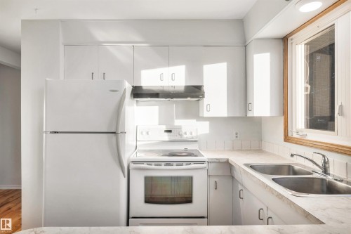 Kitchen with white range with electric cooktop, freestanding refrigerator, light countertops, and white cabinets - 11231 41 Avenue, Edmonton, AB - Indoor Photo Showing Kitchen With Double Sink