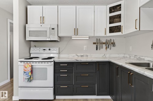 The kitchen features two-toned cabinetry, a white stove, and white countertops with grey veining - 1873 151 Avenue, Edmonton, AB - Indoor Photo Showing Kitchen
