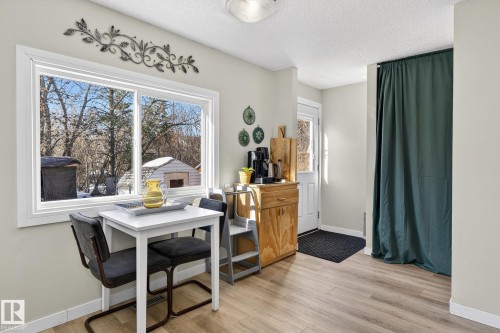 This space features light-toned flooring, a large window offering natural light, and a white door with a window - 1873 151 Avenue, Edmonton, AB - Indoor
