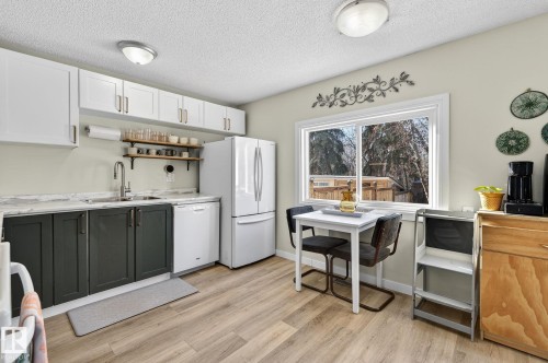 This kitchen features white upper cabinetry, dark lower cabinetry, and light-colored countertops - 1873 151 Avenue, Edmonton, AB - Indoor Photo Showing Kitchen With Double Sink