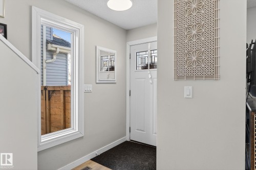 Entryway featuring a white door with decorative glass inserts, a window with white trim, and light grey walls - 1873 151 Avenue, Edmonton, AB - Indoor Photo Showing Other Room