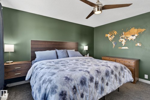 This bedroom features dark green walls, a ceiling fan with a light fixture, and dark gray carpet flooring - 1873 151 Avenue, Edmonton, AB - Indoor Photo Showing Bedroom