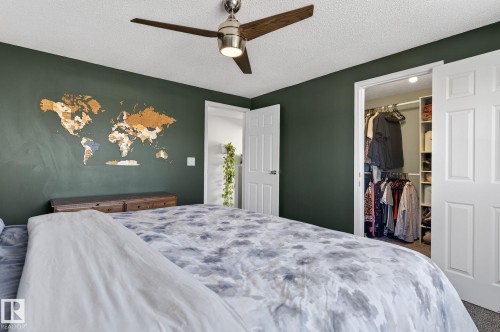 This bedroom features dark green walls, a ceiling fan with wooden blades, and a closet with bifold doors - 1873 151 Avenue, Edmonton, AB - Indoor Photo Showing Bedroom