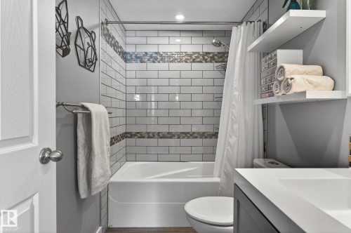 The bathroom features a tiled shower and bathtub combination, a toilet, and a vanity with a white countertop - 1873 151 Avenue, Edmonton, AB - Indoor Photo Showing Bathroom