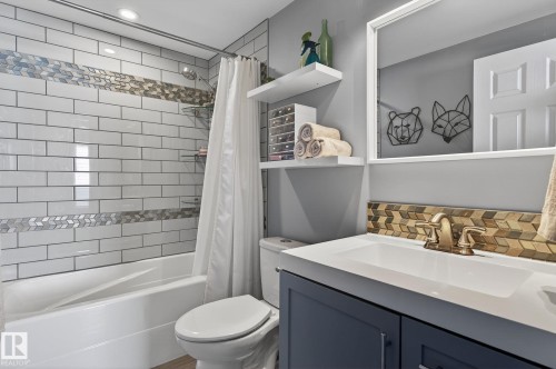 The bathroom features a white subway-tiled shower with a decorative accent band, a white bathtub, and a toilet - 1873 151 Avenue, Edmonton, AB - Indoor Photo Showing Bathroom