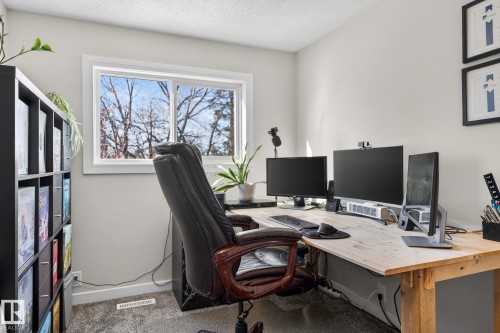 This room features a window providing natural light and views of trees, light-colored walls, and carpeting - 1873 151 Avenue, Edmonton, AB - Indoor Photo Showing Office