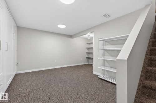 Finished lower level area featuring neutral-toned carpeting, ample built-in cabinetry with modern pulls, and recessed lighting - 1873 151 Avenue, Edmonton, AB - Indoor Photo Showing Other Room