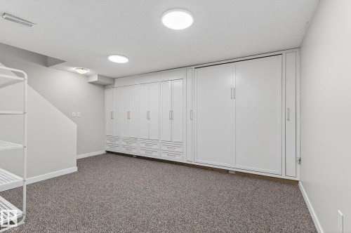This versatile space features extensive built-in cabinetry with gold-toned hardware, providing significant storage solutions - 1873 151 Avenue, Edmonton, AB - Indoor Photo Showing Other Room