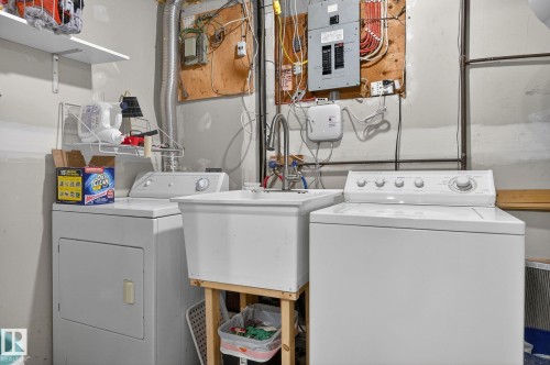 The property includes a dedicated laundry area with a white washing machine, a white dryer, and a utility sink - 1873 151 Avenue, Edmonton, AB - Indoor Photo Showing Laundry Room