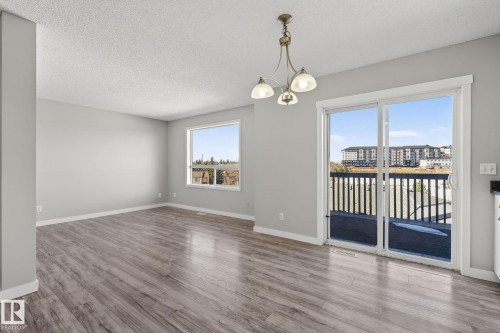 This bright interior features plank flooring, a window offering views of the outdoors, and a sliding glass door providing access to a deck with railings - 30 450 Hyndman Crescent, Edmonton, AB - Indoor