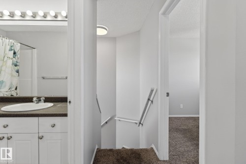 The property features a bathroom with a white vanity and a dark countertop, an oval sink, and a shower with a shower curtain - 30 450 Hyndman Crescent, Edmonton, AB - Indoor Photo Showing Bathroom