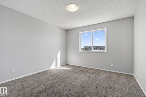 This room features a window providing natural light, grey carpeting, and light-colored walls - 30 450 Hyndman Crescent, Edmonton, AB - Indoor Photo Showing Other Room