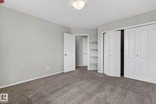 This room features neutral grey walls, textured carpet flooring, and a ceiling light fixture - 30 450 Hyndman Crescent, Edmonton, AB - Indoor