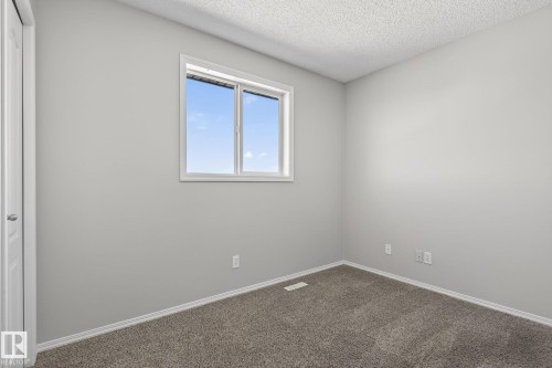 Bright room featuring a window with a white frame, light grey painted walls, and grey carpet flooring - 30 450 Hyndman Crescent, Edmonton, AB - Indoor Photo Showing Other Room