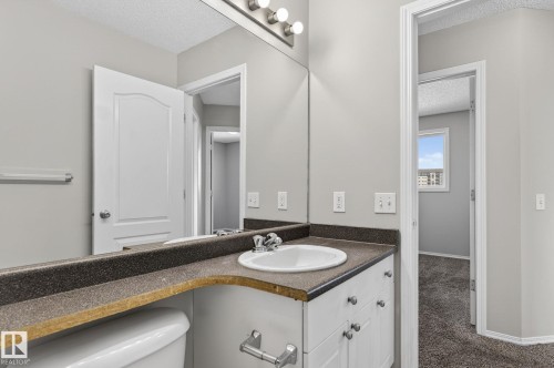 The bathroom features a white vanity with an integrated sink and a dark countertop - 30 450 Hyndman Crescent, Edmonton, AB - Indoor Photo Showing Bathroom