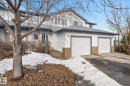 The property features a two-car garage with white doors, light-colored siding, and a brick veneer accent - 30 450 Hyndman Crescent, Edmonton, AB  - Outdoor 