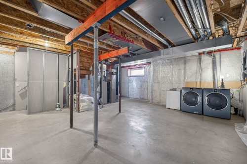 Spacious unfinished basement offering concrete flooring and visible utility infrastructure, including exposed beams and piping - 30 450 Hyndman Crescent, Edmonton, AB - Indoor Photo Showing Basement