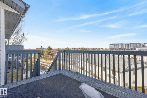 Outdoor deck area with wooden railings and a partial view of the surrounding neighborhood - 30 450 Hyndman Crescent, Edmonton, AB - Outdoor