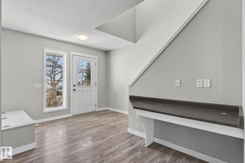 The interior features light gray walls, wood-style flooring, and a white paneled door with a window - 30 450 Hyndman Crescent, Edmonton, AB - Indoor Photo Showing Other Room