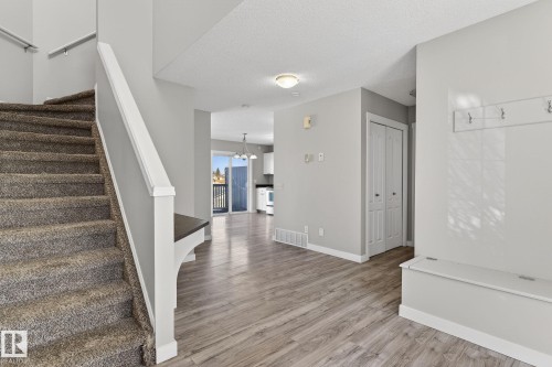 Inviting entryway featuring wood-look flooring, a storage bench, and a coat rack - 30 450 Hyndman Crescent, Edmonton, AB - Indoor Photo Showing Other Room