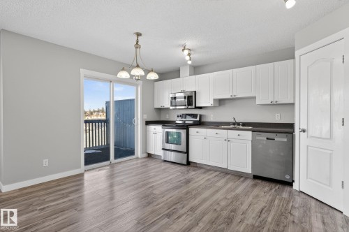 The kitchen features white cabinetry, stainless steel appliances, and a dark countertop - 30 450 Hyndman Crescent, Edmonton, AB - Indoor Photo Showing Kitchen With Double Sink