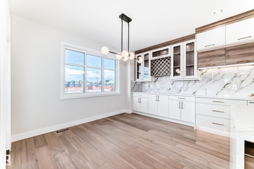 This space features light wood flooring, a large window, and a modern light fixture - 7665 Kimiwan Crescent, Edmonton, AB - Indoor