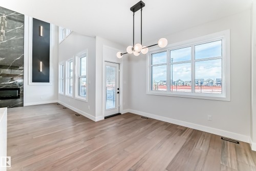 This open-concept interior features light-toned hardwood flooring throughout - 7665 Kimiwan Crescent, Edmonton, AB - Indoor Photo Showing Other Room