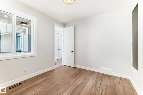 This room features hardwood flooring, white walls, and a window with white trim - 7665 Kimiwan Crescent, Edmonton, AB - Indoor Photo Showing Other Room