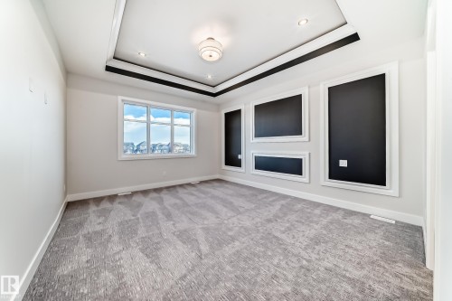 This spacious room features a tray ceiling with recessed lighting and a central light fixture - 7665 Kimiwan Crescent, Edmonton, AB - Indoor Photo Showing Other Room