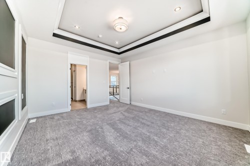 This room features a tray ceiling with recessed lighting and a central light fixture, along with a patterned carpet - 7665 Kimiwan Crescent, Edmonton, AB - Indoor Photo Showing Other Room With Fireplace