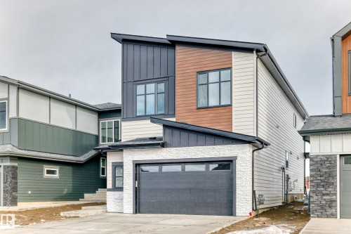 The property features a contemporary architectural style with varied siding materials, including light-colored horizontal siding, wood-toned vertical panels, and dark grey vertical siding - 7665 Kimiwan Crescent, Edmonton, AB - Outdoor