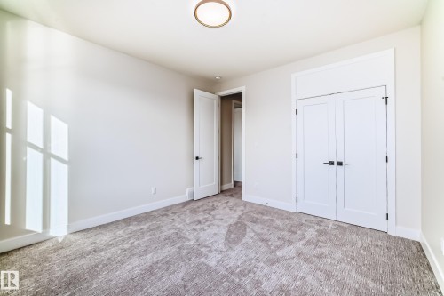 Bright room featuring a ceiling light fixture, white walls, and light-colored patterned carpet - 7665 Kimiwan Crescent, Edmonton, AB - Indoor Photo Showing Other Room