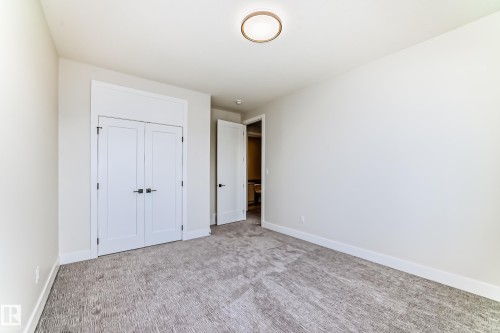 This room features light-colored walls, gray carpet flooring, and a ceiling light fixture - 7665 Kimiwan Crescent, Edmonton, AB - Indoor Photo Showing Other Room