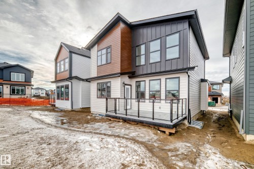 The property features a modern exterior design with mixed siding, including light-colored horizontal siding, dark vertical siding, and wood-toned paneling - 7665 Kimiwan Crescent, Edmonton, AB - Outdoor