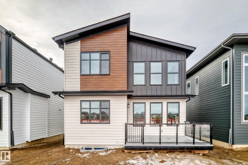 The property features a contemporary design with a combination of light-colored siding, natural wood-tone accents, and dark vertical paneling - 7665 Kimiwan Crescent, Edmonton, AB - Outdoor With Exterior